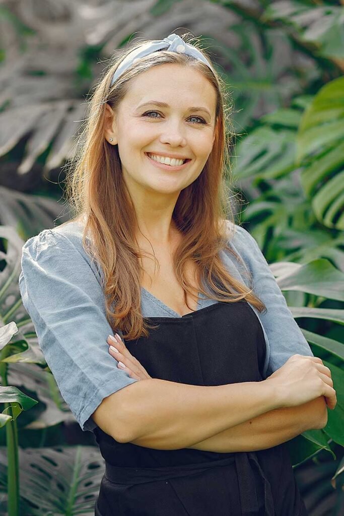Woman In A Black Apron Working In A Greenhouse 92xvtkj.jpg